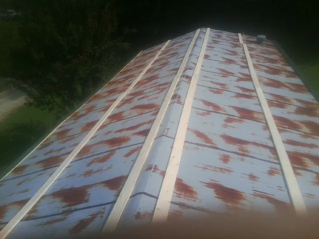 Rusted metal roof panels with new wood purlins before replacement — Storm Damage Roof Repair in Volga by Roofing Brothers