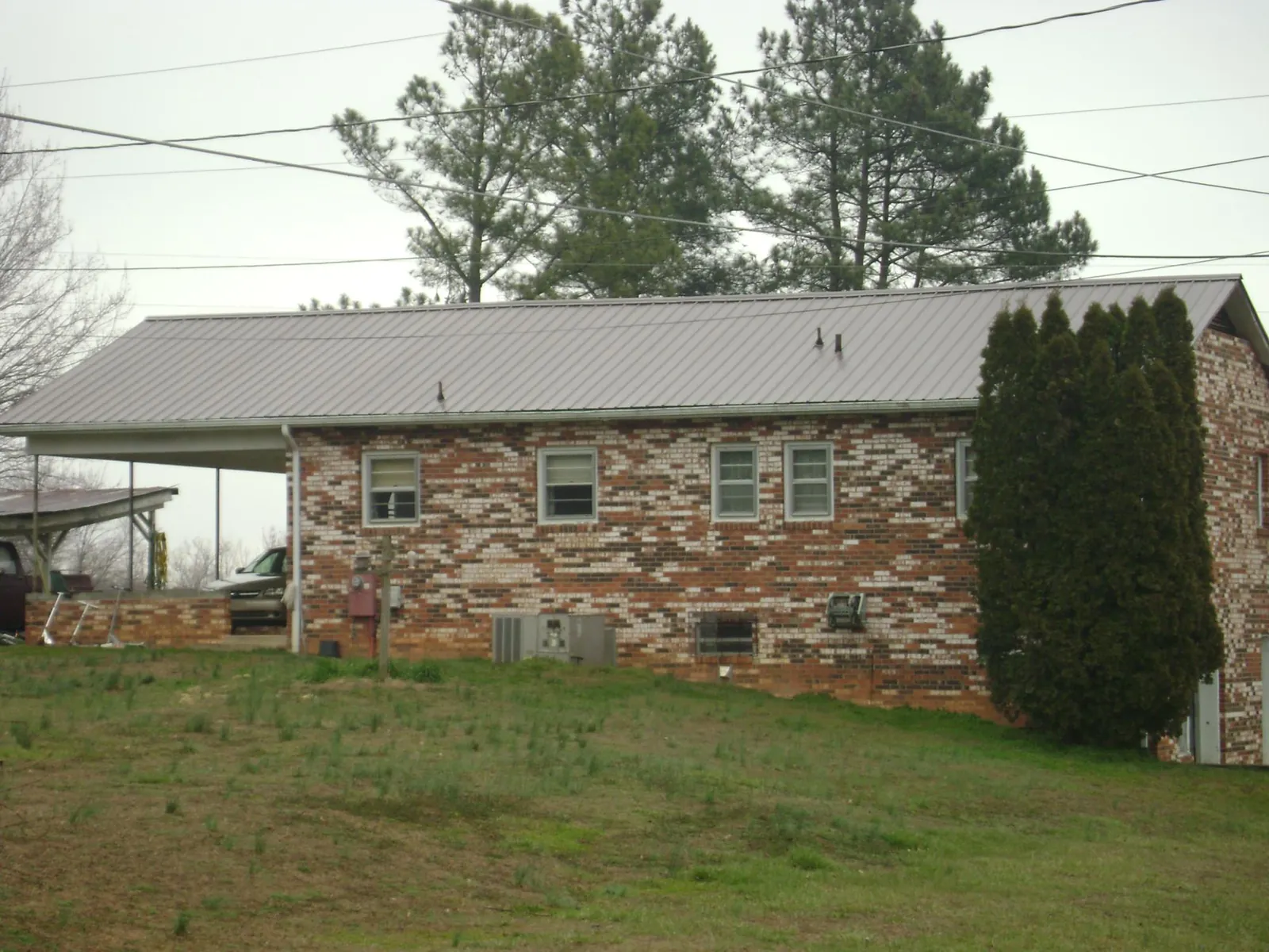 Gray metal roof on a brick split level home with a carport in Volga