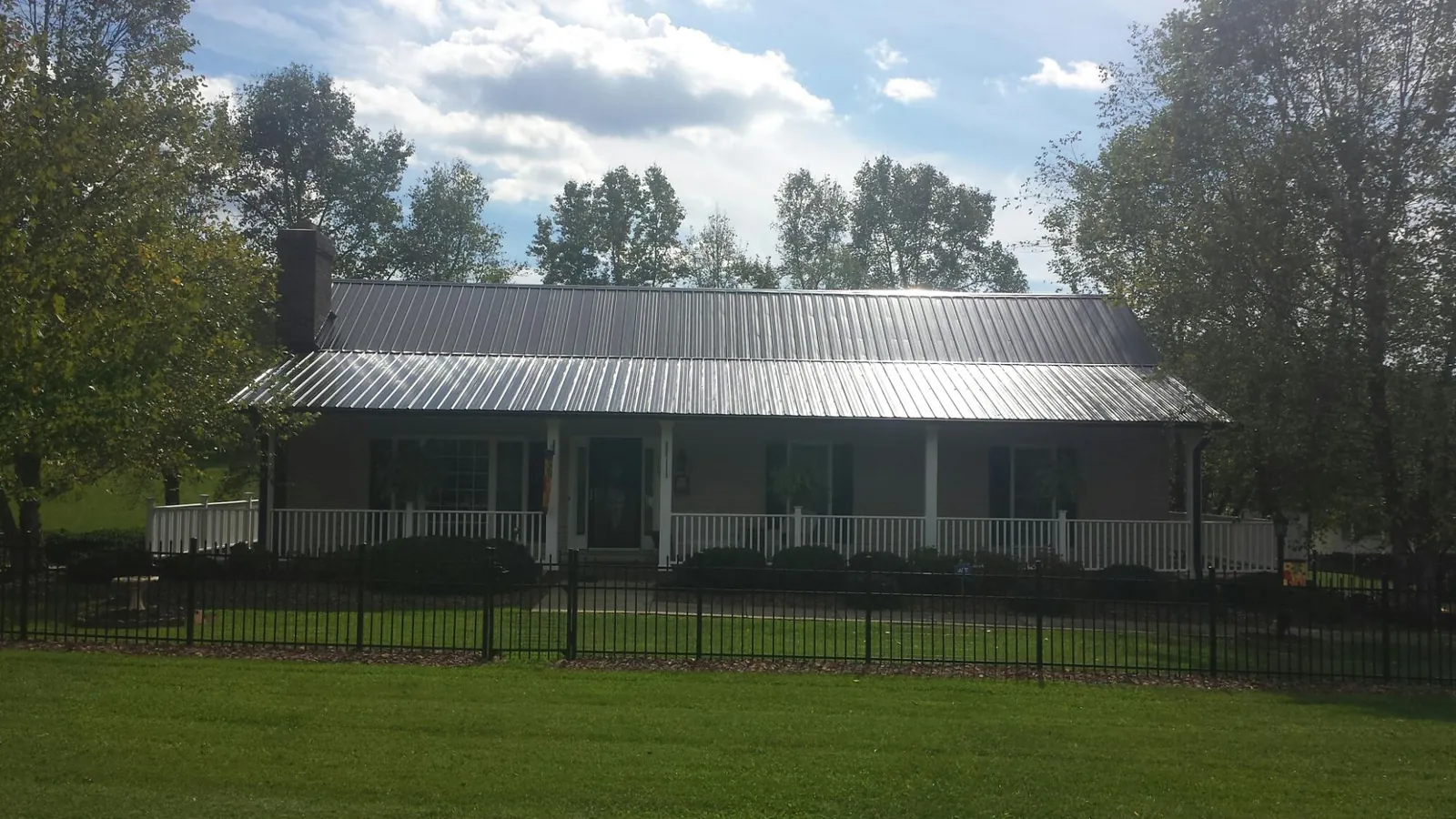 Gray metal roof on a brick ranch with a full width front porch — Gutter Guard Installation work by our crew in Volga