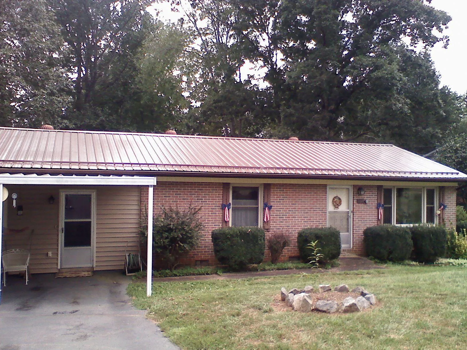 Bronze metal roof and carport on a brick ranch home — Roof Repair work by our crew in Volga