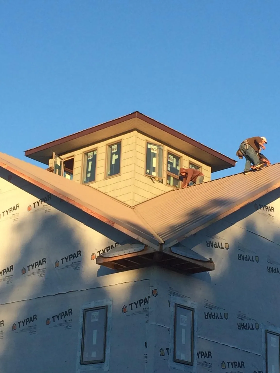 Roofers working around a rooftop cupola on a new metal roof at sunset — Roof Waterproofing in Volga by Roofing Brothers